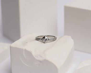 Alyans beyaz taşa takılmış. Mücevher yüzüğü sergilenip satılmaya hazır. Alyans, bu çiftin aşkının bir işareti. İnciler ve elmaslar yüzüğün güzelliğini tamamlıyor. odak bulanıklığı.