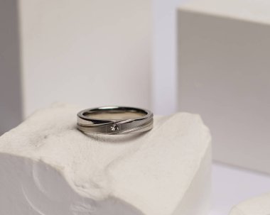 Alyans beyaz taşa takılmış. Mücevher yüzüğü sergilenip satılmaya hazır. Alyans, bu çiftin aşkının bir işareti. İnciler ve elmaslar yüzüğün güzelliğini tamamlıyor. odak bulanıklığı.