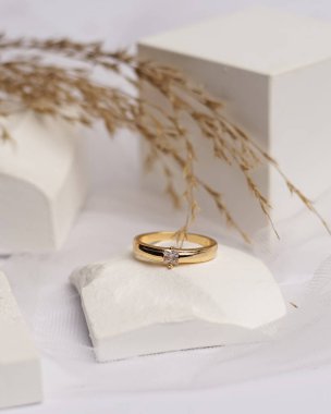 Alyans beyaz taşa takılmış. Mücevher yüzüğü sergilenip satılmaya hazır. Alyans, bu çiftin aşkının bir işareti. İnciler ve elmaslar yüzüğün güzelliğini tamamlıyor. odak bulanıklığı.