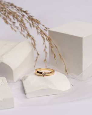 Alyans beyaz taşa takılmış. Mücevher yüzüğü sergilenip satılmaya hazır. Alyans, bu çiftin aşkının bir işareti. İnciler ve elmaslar yüzüğün güzelliğini tamamlıyor. odak bulanıklığı.