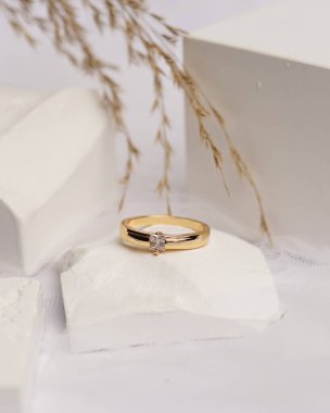 Alyans beyaz taşa takılmış. Mücevher yüzüğü sergilenip satılmaya hazır. Alyans, bu çiftin aşkının bir işareti. İnciler ve elmaslar yüzüğün güzelliğini tamamlıyor. odak bulanıklığı.