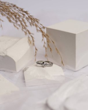 Alyans beyaz taşa takılmış. Mücevher yüzüğü sergilenip satılmaya hazır. Alyans, bu çiftin aşkının bir işareti. İnciler ve elmaslar yüzüğün güzelliğini tamamlıyor. odak bulanıklığı.