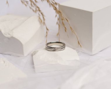 Alyans beyaz taşa takılmış. Mücevher yüzüğü sergilenip satılmaya hazır. Alyans, bu çiftin aşkının bir işareti. İnciler ve elmaslar yüzüğün güzelliğini tamamlıyor. odak bulanıklığı.