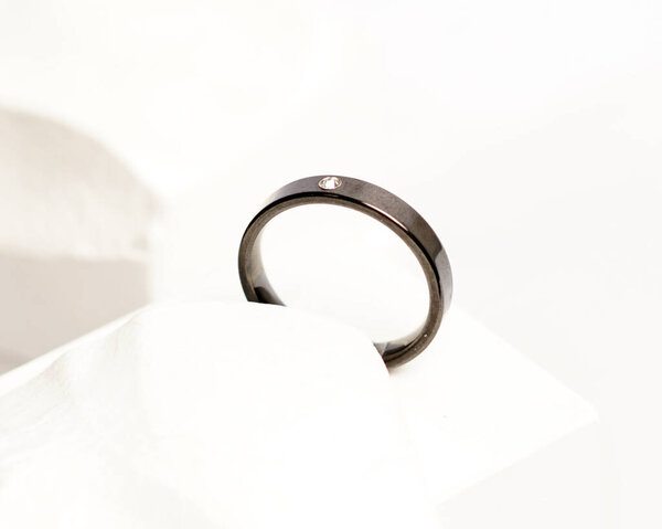 Бриллиантовое кольцо для отображения в социальных сетях. Обручальное кольцо сфотографировано на белом камне. Обручальное кольцо из драгоценных камней. Свадебные кольца изолированы на ярком белом фоне, фокус размыт. Золотое кольцо.