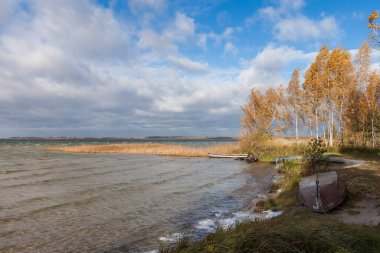 Rüzgarlı sonbahar havasında göl kenarındaki eski tekneler