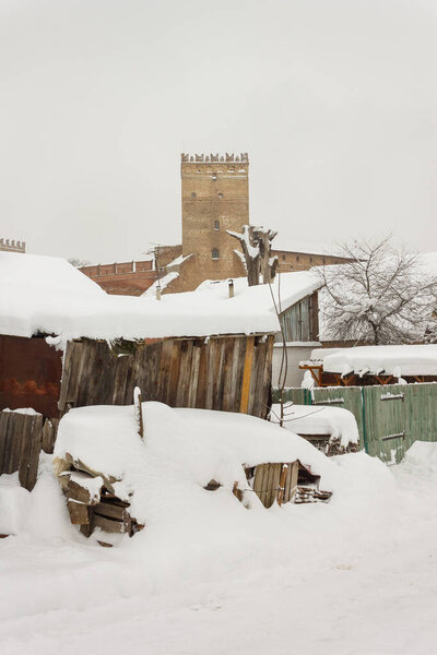Old houses on the background of a medieval castle in winter. Ukraine