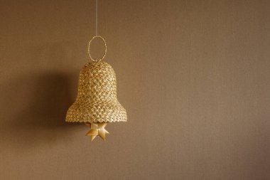 Bej arka planda samandan yapılmış çan. Hasır çan süslemeleri. Uzayı kopyala Arkaplan