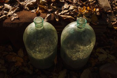 İki eski cam şişe sarı akşam güneşi ışığıyla aydınlatılır.