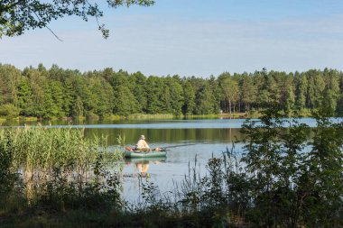 Lastik bir teknede bir balıkçı gölde balık yakalar.