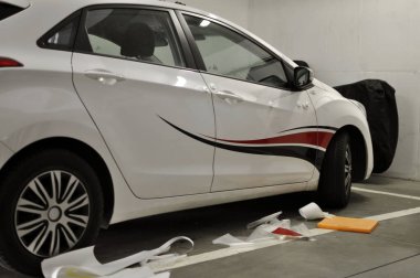Brno, Çek Cumhuriyeti - 25 Nisan 2020: Garajda beyaz bir arabaya folyo çıkartması yapıştırmak 