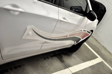 Brno, Çek Cumhuriyeti - 25 Nisan 2020: Garajda beyaz bir arabaya folyo çıkartması yapıştırmak 