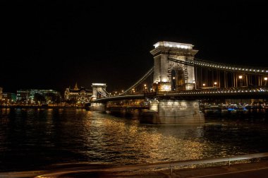 Budapeşte, Macaristan - 09 Ekim 2012: Budapeşte 'deki eski ışınlanmış Zincir Köprüsü' nün gece görüşü Tuna Nehri 'ne yansıdı. Arka planda şehrin tarihi evlerini görebilirsiniz..