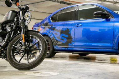 Brno, Çek Cumhuriyeti - 17 Kasım 2021: Mavi spor araba ve siyah motosiklet yeraltı garajına park edildi. Arabanın yan tarafında siyah parlak folyodan yapılmış çıkartmalar var..