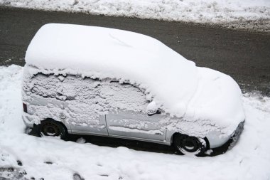 Şehirde kar fırtınası sırasında yeni yağmış bir araba. Araba karlı bir yolda park edilmiş..