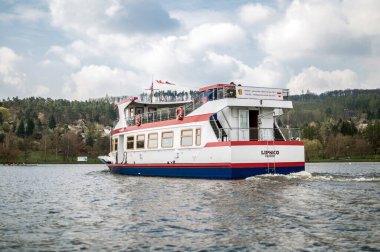 Brno 'da bir barajın yüzeyinde turistler için beyaz bir yolcu gemisi yüzüyor..