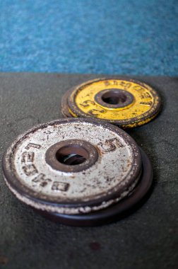 Spor salonunda eski metal halterler aşınmış. Güçlendirmek için yuvarlak renkli ağır ağırlıklar.