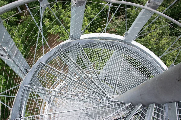 Yüksek çelik gözetleme kulesinin yuvarlak merdiveni. Merdivenler ana destek sütununda asılı. Aşağıya, yere ve ormana bakın..