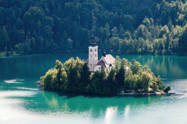 An island with a church with a tall tower in the middle of Lake Bled in Slovenia.