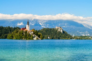 Slovenya 'da Bled Gölü' nün ortasındaki bir adadaki kilise. Güneş ışığı ile aydınlanan kilise kulesi göldeki yansımayla..