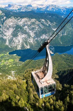 Slovenya 'daki Vogel Dağı' nın tepesine kadar uzanan bir halatı takip eden kablo kabini. Vadide Bohinj Gölü var..