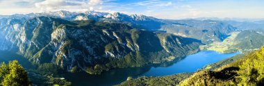 Slovenya 'daki yüksek kayalık Julian Alpleri' nin panoramik fotoğrafı ve vadide mavi Bohinj gölü..