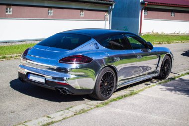 Parlak krom rengi (folyo folyo) olan pahalı lüks spor araba sokağa park edilmiş..