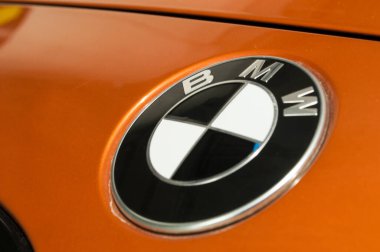 Turuncu bir spor arabanın kaputunda siyah araba üreticisi logosu..