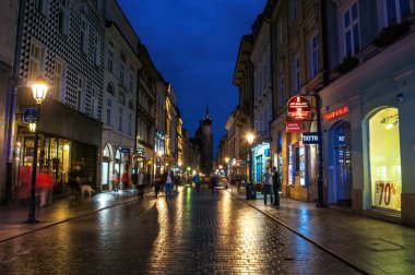 Krakow, Polonya - 18 Temmuz 2016: Eski kentin ana caddelerinden biri kaldırımda yanan binalar ve yansımalarla ana meydana çıkıyor