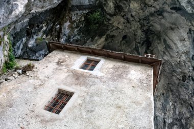 Slovenya 'daki Predjama Kalesi. Yüksek bir kayanın altında pencereleri olan kale kulesi..