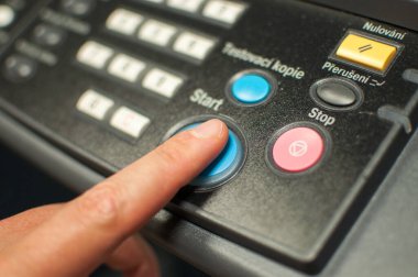 Başlatma düğmeleri olan makine kontrol paneli yazdırılıyor. İşçi eli, parmak güç düğmesine basıyor..