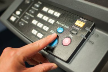 Başlatma düğmeleri olan makine kontrol paneli yazdırılıyor. İşçi eli, parmak güç düğmesine basıyor..