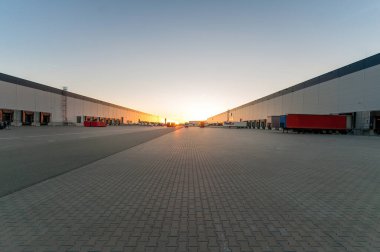 Gün batımında koridorları ve kamyonları olan lojistik alanı. Malların taşınması ve depolanması.