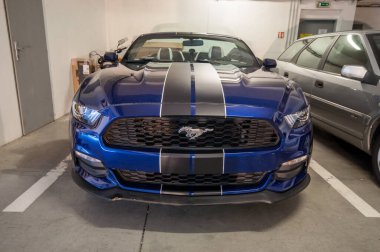 Mavi spor Amerikan arabası garajda. Matt Black Folyo şeritlerinin servis ve kurulumu. Kaputa çıkartma yapıştırılıyor.