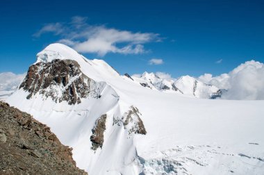 İsviçre 'de yaz mevsiminde buzullar kar tabakasıyla kaplıdır. Yüksek kayalık dağlar, dağlarda yürüyüş için bir patika..