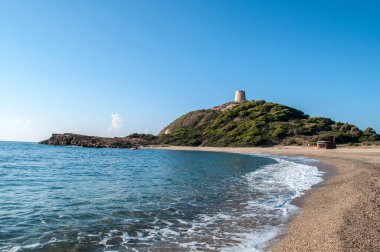 Dağlardaki kumsal ve arka plandaki eski kule (Sardunya)