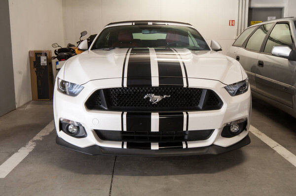 Установка (склеивание, нанесение) черных полос наклейки глянцевой черной фольги на белый спортивный мускул-кар в гараже.