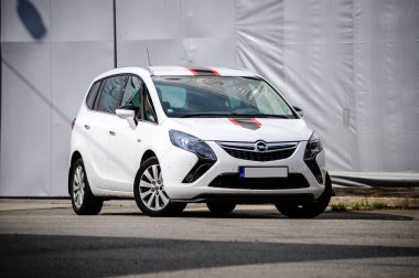 Beyaz modern aile arabası gri ve kırmızı teneke bir salonun yanındaki sanayi bölgesine park edilmiş. Folyo kaputunda etiket.