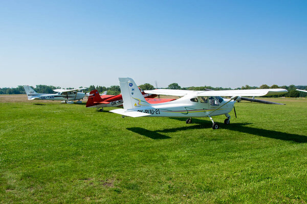 A small sporty white plane is parked on the airport meadow.