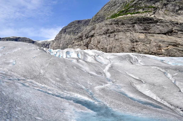 ノルウェーの湖の上の岩の多い山々の真ん中にある巨大なヨステダレン氷河 — ストック写真