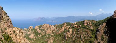 View of sunlit mountains and sea in Calanches area on Corsica island