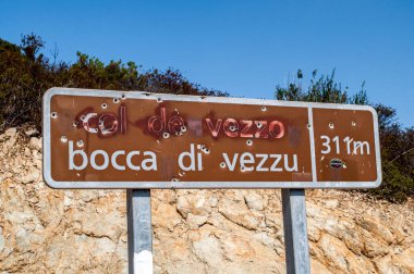A painted and shot road sign with the name of the city and a direction indicator. A destroyed sign on the island of Koriska in France.