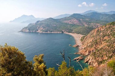 Porto şehrinin yakınında kumlu bir plajı olan Korsika adasının kıyısında. Denizin üzerindeki kayalar batan güneşin aydınlattığı kayalar..
