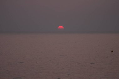 Adanın dağlarıyla çevrili sahilde gün batımı Porto Ota, Korsika