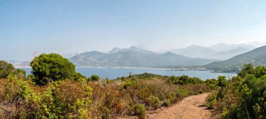 A bay named Galeria on the island of Corsica. Panorama of clear azure sea, coast with fine sand on the beach and mountains in the background.