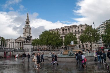 Londra, Birleşik Krallık - 10 Temmuz 2012: Londra 'da su birikintileri ve mavi gökyüzü ile Trafalgar Meydanı. Ulusal müze, çeşme ve heykel.