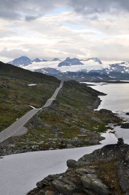 Norveç 'in Sognefjellet bölgesinde 55 numaralı dalgalı yol, yıl boyunca karla kaplı dağlar ve donmuş göller etrafında koşuyor.