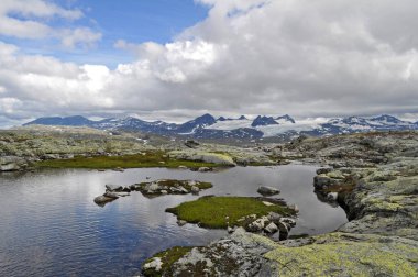 Sognefjell, Jotunheim, Norveç. Doğal parktaki karlı kayalık arazi. Karla kaplı kayalar, dağlar ve buzlu göller..