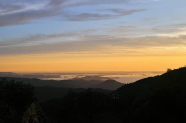 Günbatımı, Norveç Preikestolen parkında deniz ve dağlar üzerindeki turuncu bulutlar