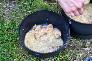 Yemek hazırlamak (domuz ve lahana) dışarıda teneke bir tencerede.