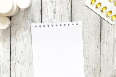 Tıbbi konsept. Masanın üzerinde tabletler, bir yaprak kağıt, tahta zemin üzerinde bir kalem var. Metnin için yer.